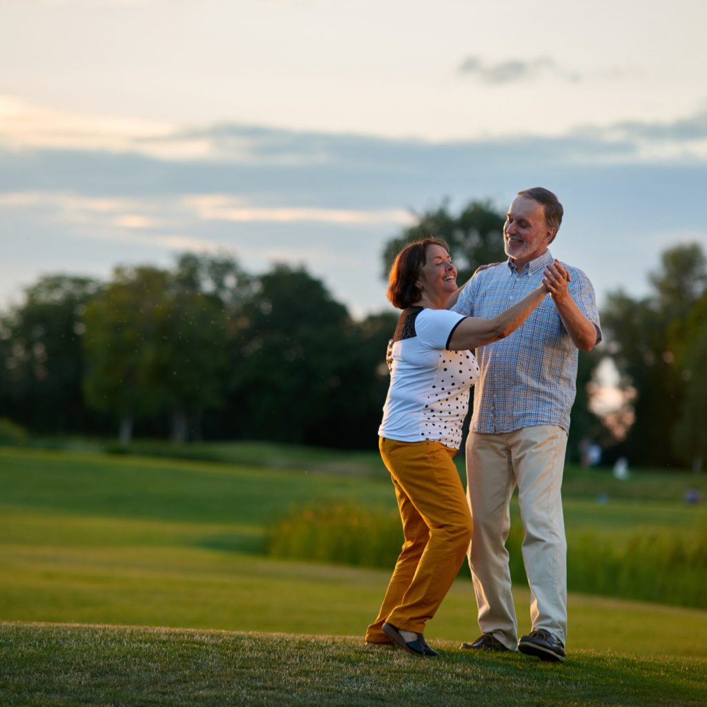 Happy loving couple dancing outdoors. Mature caucasian man and his wife.